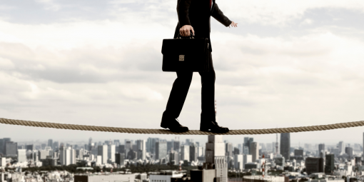 Ein Mann im Anzug balanciert auf einem Seil mit der Skyline einer Stadt im Hintergrund